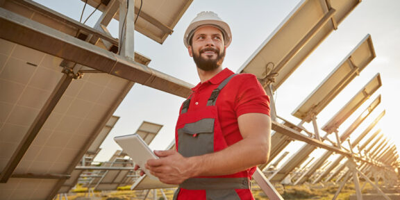 Man wearing hardhat near solar panels.